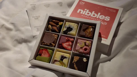 An open Nibbles chocolate assortment beside its branded packaging in Yeaji’s post
