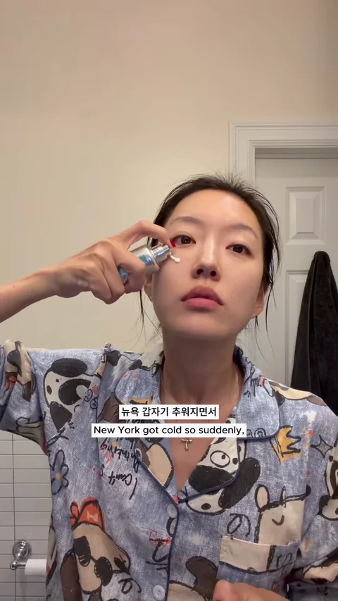 Yeaji applying skincare to her cheek while wearing patterned pajamas at home